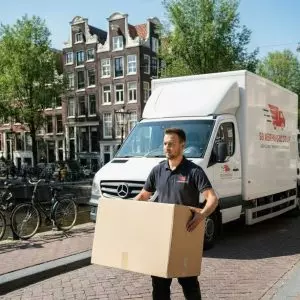 Verhuizer van SB Verhuisbedrijf draagt een verhuisdoos naar de verhuiswagen.